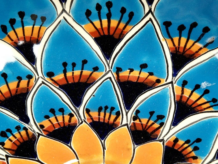 Detailansicht einer handbemalten Keramikfliese mit floralem Muster