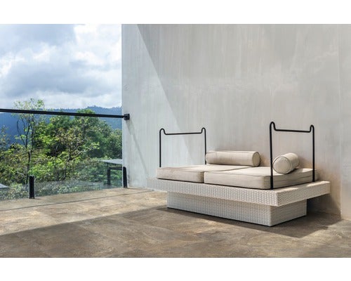 Doppelliege aus Rattan mit Kissen auf einer Terrasse mit Ausblick