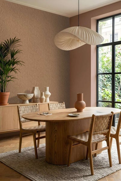Esszimmer mit gemusterter Vliestapete, Holztisch, Stühlen mit Flechtwerk und moderner Pendelleuchte in natürlichem Wohnambiente.