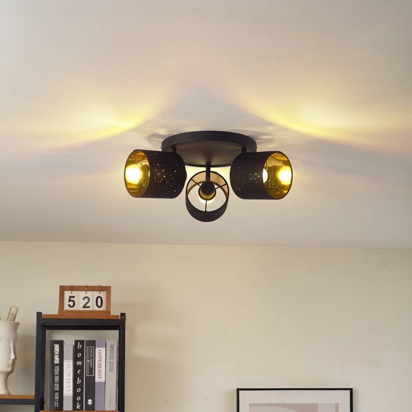 Deckenleuchte mit drei Strahlern, schwarze Metallschirme mit Perforation für Sterneneffekt, goldene Innenseite, modernes Wohnraumdesign.