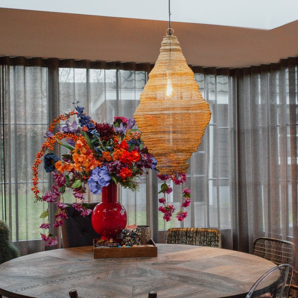 Esstisch mit Blumenstrauß in roter Vase und Hängelampe