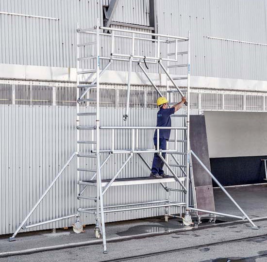 Rollgerüst mit Arbeiter in Arbeitskleidung und Schutzhelm.