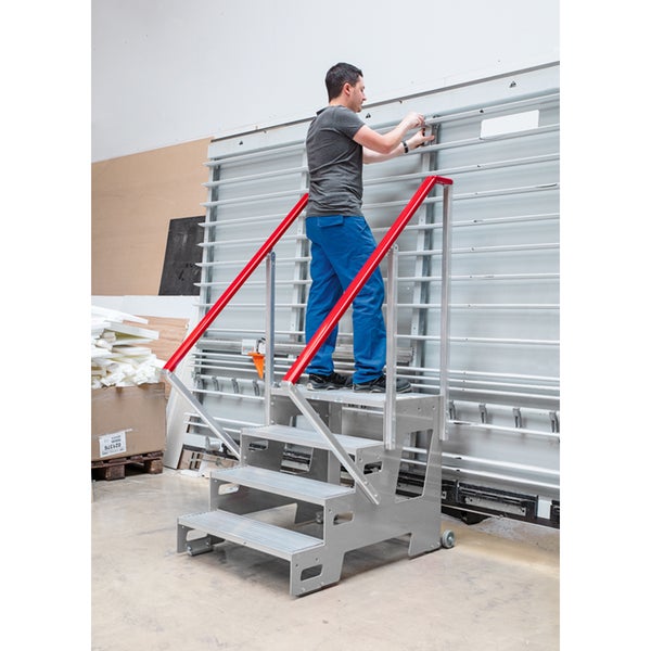Mann auf Montagetreppe mit roten Handläufen vor Plattenzuschnittsäge