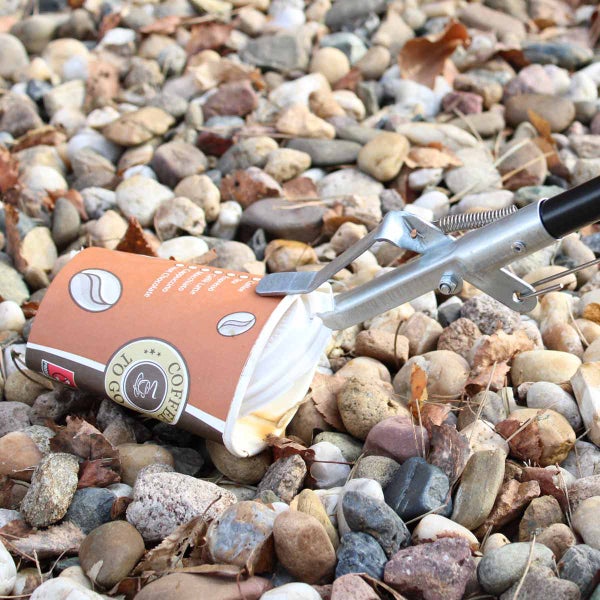 Müllgreifer nimmt einen Coffee-to-go-Becher vom Boden auf