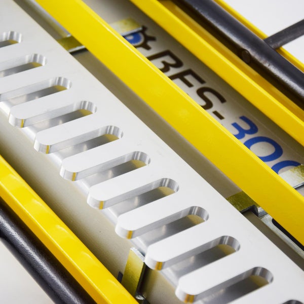 Detailaufnahme einer silberfarbenen Kabelführung mit Aussparungen und gelben sowie schwarzen Führungselementen.