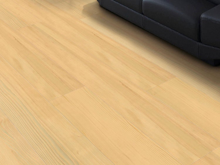 Bodenbelag in heller Holzoptik mit natürlicher Maserung, verlegt in einem hellen Raum neben einem dunklen Sofa.