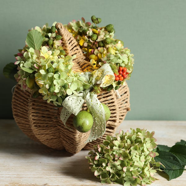 Dekorative Kürbis-Korb-Arrangement mit Hortensien und Schleife