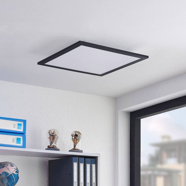 Quadratisches LED-Panel mit schwarzem Rahmen in einem hellen Büro mit Regal und Fenster.