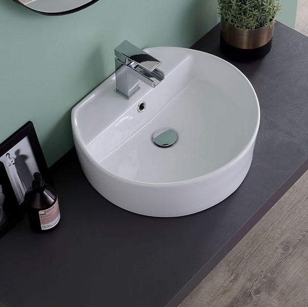Modernes weißes Aufsatzwaschbecken aus Keramik mit verchromter Armatur auf einer dunklen Arbeitsplatte im Badezimmer.