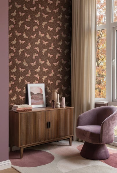 Wohnraum mit brauner Tapete mit Schmetterlingsmuster, einem Sideboard aus Holz, einem lila Sessel, einem gemusterten Teppich und einem Fenster.