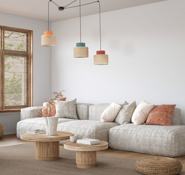 Wohnzimmer mit Couch, Teppich, Tisch und dreiflammiger Pendelleuchte