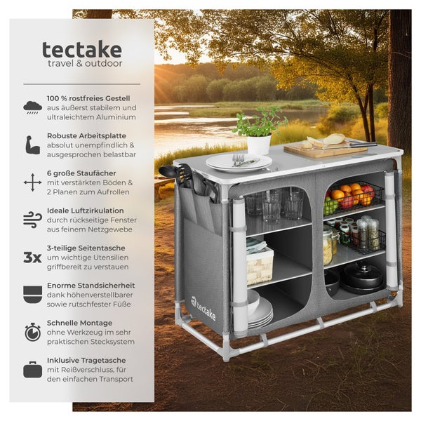 Campingküche mit Aluminiumgestell, Arbeitsplatte, sechs Staufächern und Seitentaschen vor ländlicher Kulisse