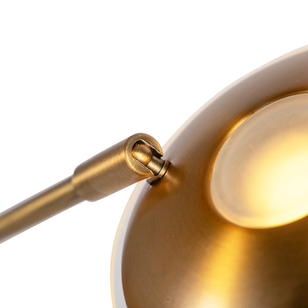 Nahaufnahme einer goldenen Lampe mit verstellbarem Gelenkarm.