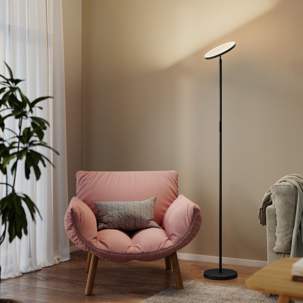 Moderne schwarze LED-Stehleuchte als Deckenfluter in einem hellen Wohnzimmer mit rosa Sessel und Holzfußboden.