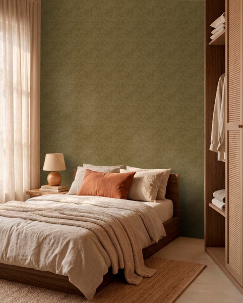 Schlafzimmer mit dunkelgrüner strukturierter Tapete, Holzbett mit heller Bettwäsche, Nachttisch mit Lampe und offenem Kleiderschrank aus Holz.