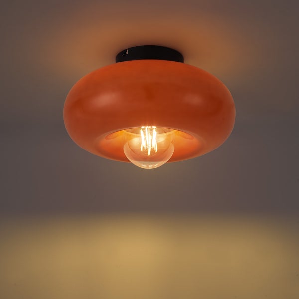 Orangefarbene, ringförmige Deckenleuchte aus Glas mit schwarzer Halterung und leuchtendem Filament-Leuchtmittel.