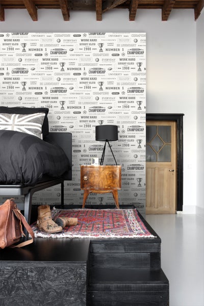 Dekoriertes Schlafzimmer mit Bett und Nachttisch vor einer gemusterten Tapete