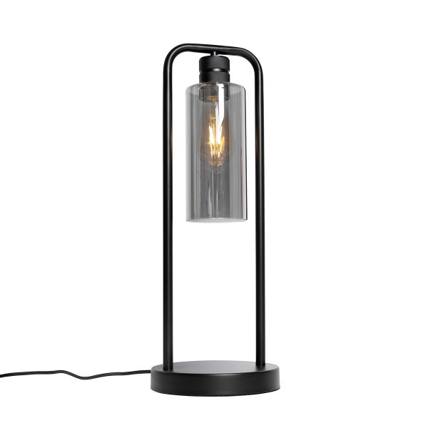 Tischleuchte mit schwarzem Metallgestell in Bogenform, rundem Fuß und zylindrischem Schirm aus Rauchglas inklusive sichtbarem Leuchtmittel.