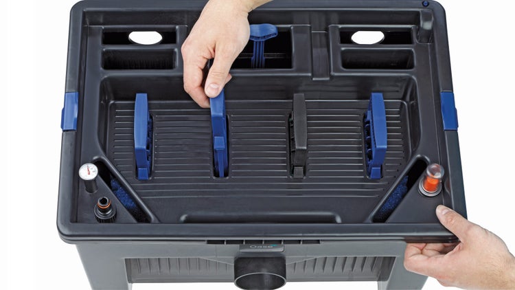 Oase Teichfilter Innenansicht mit Reinigungsschwämmen, Thermometer und blauen Handgriffen zur Reinigung, Oase Logo.