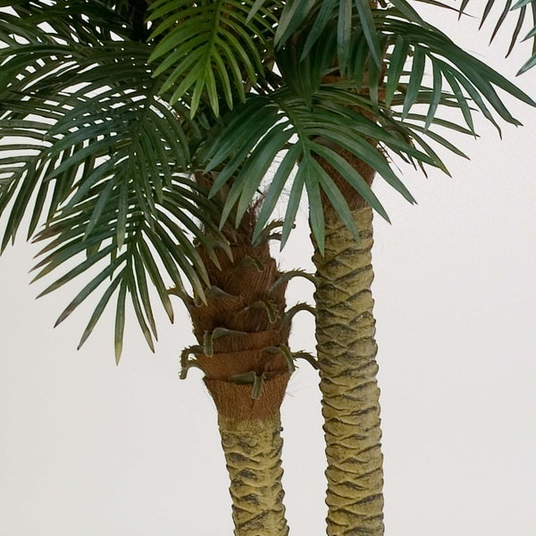 Nahaufnahme von zwei strukturierten Stämmen einer künstlichen Palme in einem schwarzen Kunststofftopf.