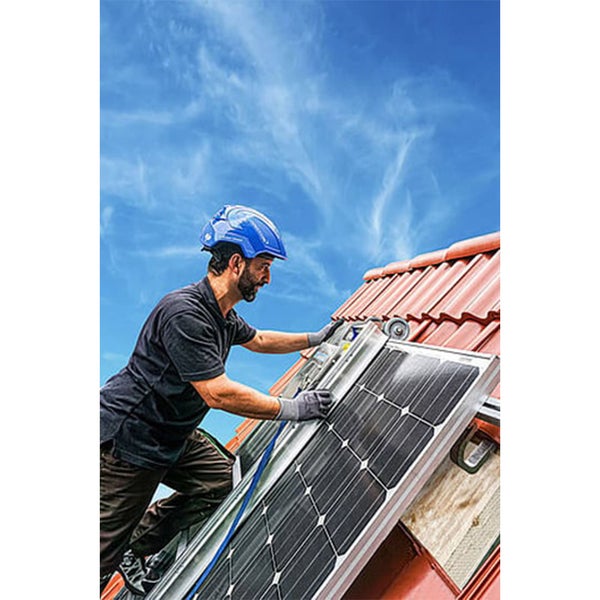 Handwerker mit Schutzhelm bei der Montage einer Photovoltaikanlage auf einem Ziegeldach.