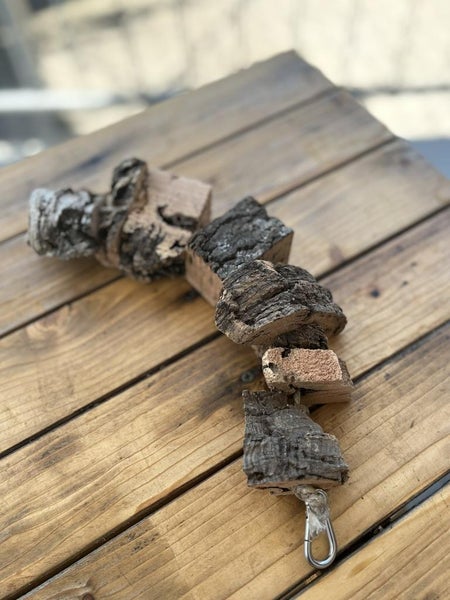 Vogelspielzeug aus Korkrinde an einem Seil mit Karabinerhaken.