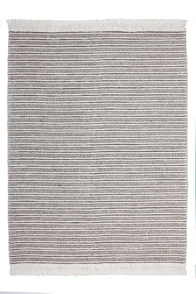 Modernes Wohnzimmer mit grauer Wand in Spachteloptik, Stoffsofa, gemusterten Dekokissen, großer Studio-Stehleuchte und gestreiftem Teppich.