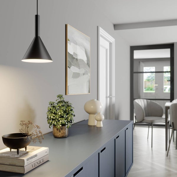 Schwarze kegelförmige Pendelleuchte in modernem Interieur über einem Sideboard mit Deko und Zimmerpflanze in einer hellen, organisierten Umgebung.