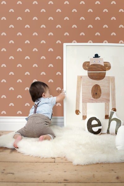 Zimmer mit Tapete mit Regenbogenmuster, Poster mit Affenillustration und Kind auf einem Schaffellteppich.