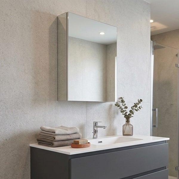 Moderner Spiegelschrank über einem dunklen Waschtischunterschrank mit weißem Waschbecken in einem hellen Badezimmer mit Steinoptik-Wänden.