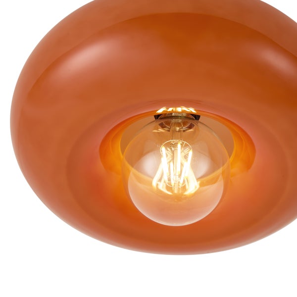 Nahaufnahme einer Deckenleuchte mit glänzendem, rundem Glasschirm und einer eingeschalteten LED-Filament-Glühbirne.