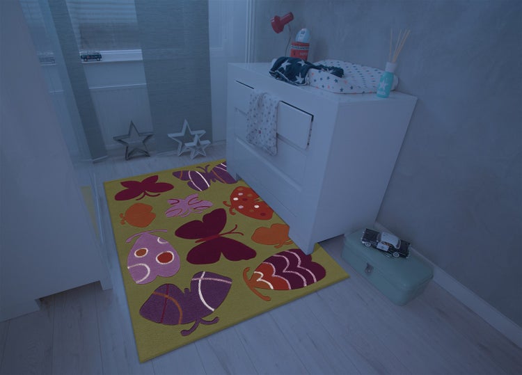 Kinderteppich mit Schmetterlingsmotiv in einem modern eingerichteten Kinderzimmer vor einer weißen Kommode.