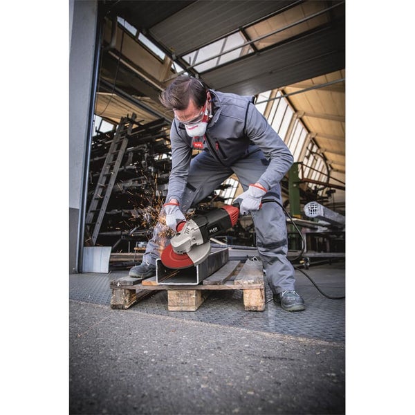 Handwerker mit Schutzbrille und Atemschutz beim Trennen eines Metallprofils mit einem Flex Winkelschleifer in einer Werkstatt.