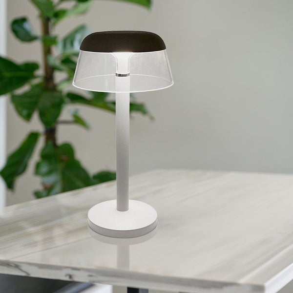 Tischleuchte mit transparentem Schirm und schlankem Design auf einem Tisch
