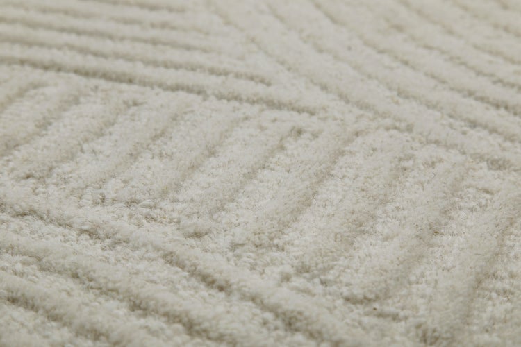 Detailaufnahme eines Teppichs mit geometrischem Linienmuster und strukturierter Oberfläche.