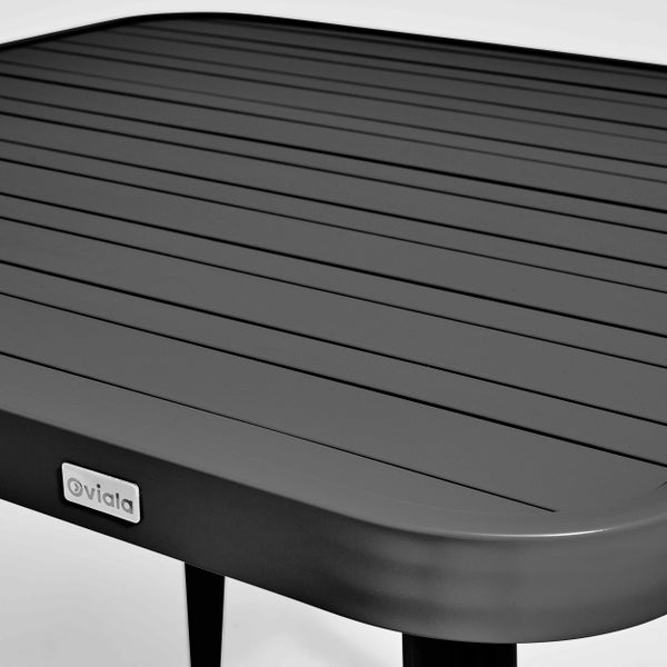 Detailaufnahme einer Tischplatte aus grauen Aluminium-Lamellen mit abgerundeten Ecken und Oviala Logo.