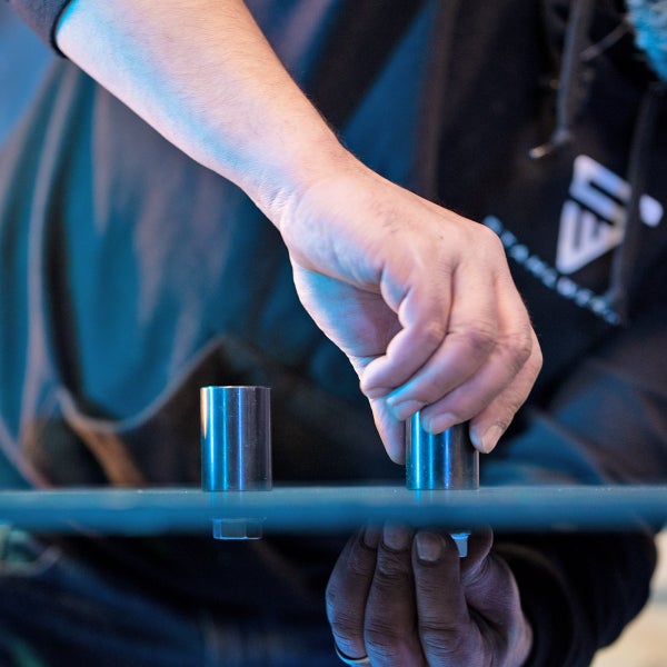 Eine Person platziert zwei Metallzylinder auf einer glatten Oberfläche.