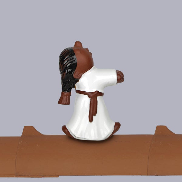 Firstfigur aus Keramik, Karatekämpfer in weißem Anzug auf einem braunen Firstziegel.