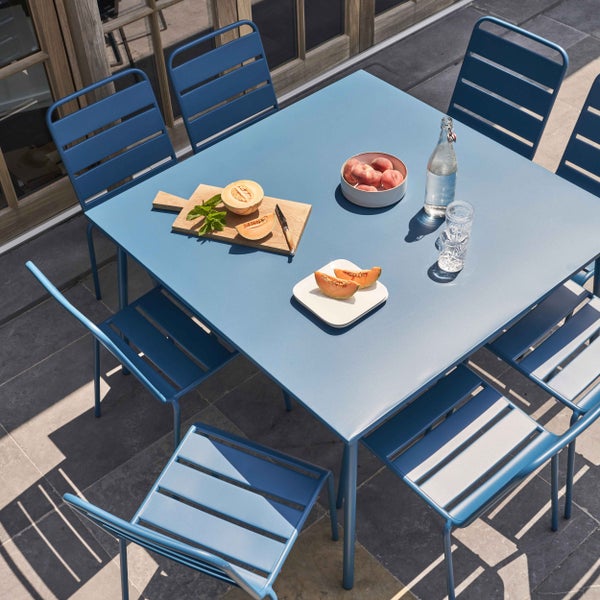 Quadratischer Tisch aus Metall in Blau mit vier runden Beinen.