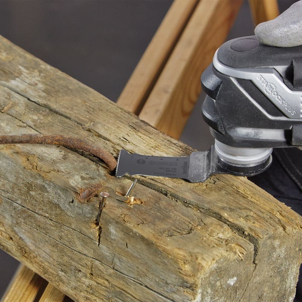Oszillierendes Elektrowerkzeug mit Bosch Metallsägeblatt schneidet Nagel in einem Holzstück.