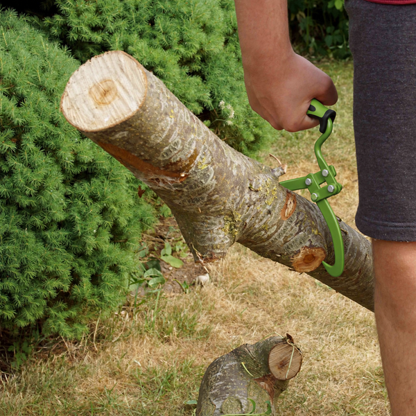 Eine Hand hält eine Holzgreifzange, die einen Baumstamm im Garten greift und anhebt.
