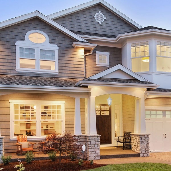 Ansicht eines zweistöckigen Wohnhauses mit Holzfassade, Fenstern und einer Veranda mit Säulen