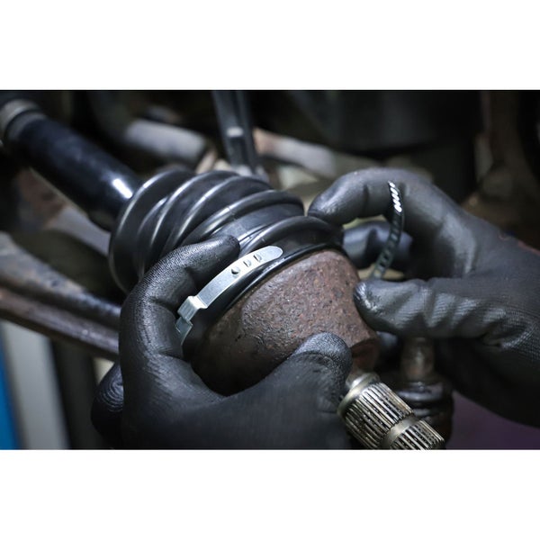 Eine Person befestigt eine Manschette an einer Antriebswelle mit einer Zange.