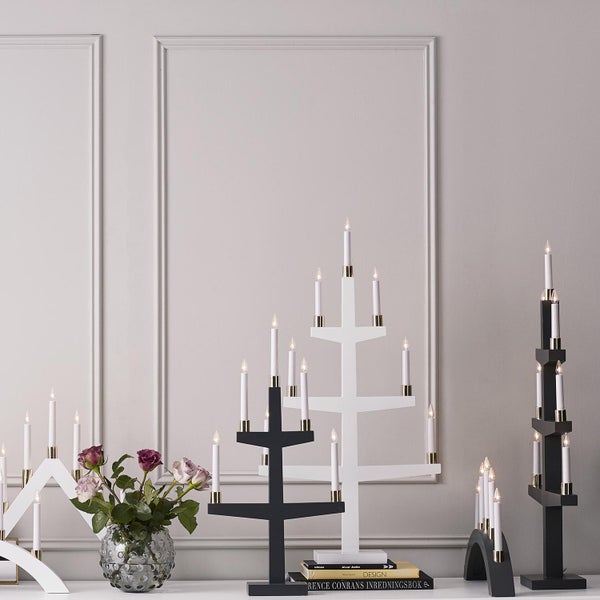 Dekorative Anordnung von elektrischen Kerzenleuchtern mit verschiedenen Designs auf einer Tischplatte, ergänzt durch eine Blumenvase.