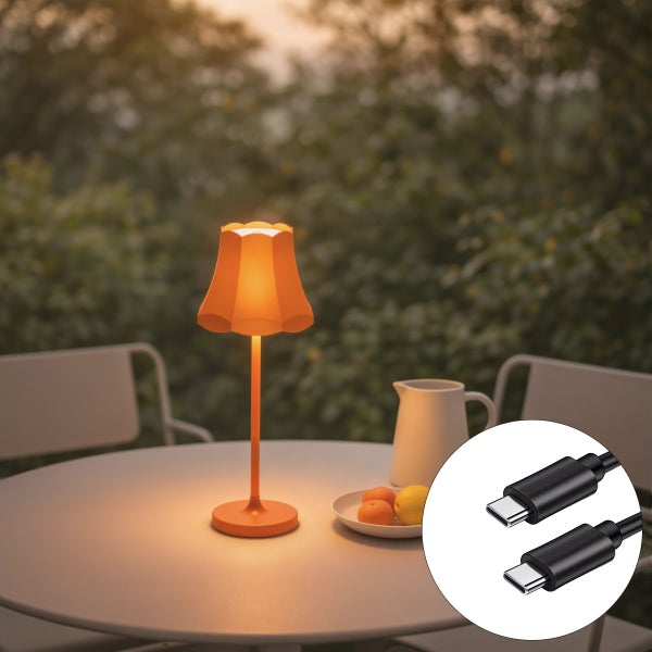 Moderne orangefarbene LED-Tischleuchte auf einem weißen Gartentisch mit USB-C-Anschluss, Gartenmöbeln und grünem Außenbereich.