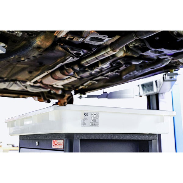 Weiße Kunststoff-Auffangwanne für Öl unter einem Fahrzeug auf einer Hebebühne in einer Werkstatt. BGS technic Logo auf dem Wagen.