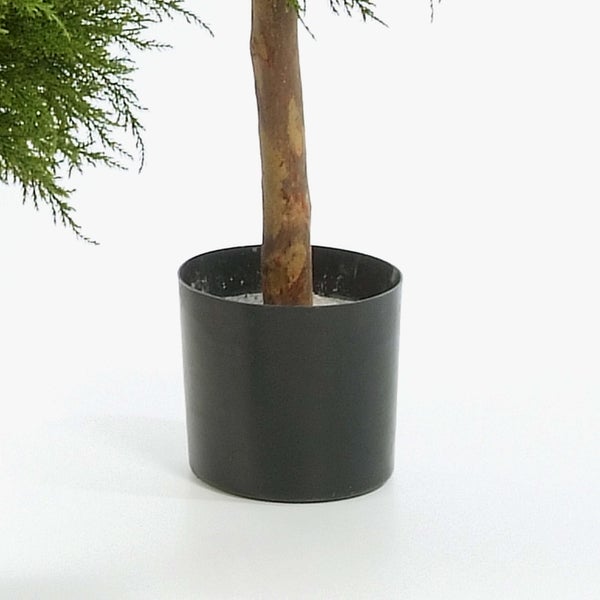 Künstliche Pflanze mit Holzstamm in einem schwarzen Kunststofftopf.