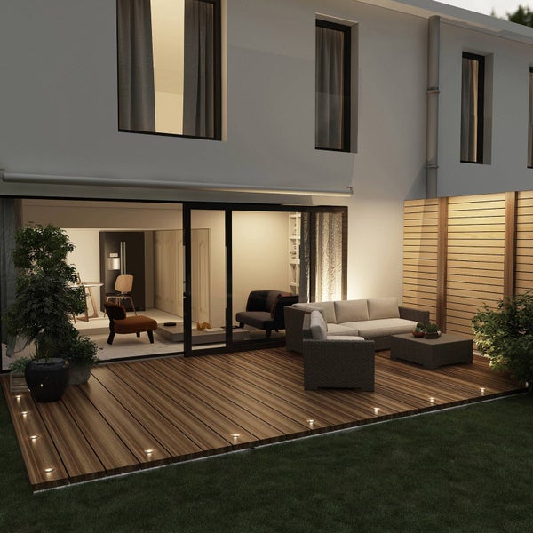 Moderne Holzterrasse mit integrierten Bodenspot-Leuchten, Outdoor-Lounge-Möbeln und Holz-Sichtschutzzaun an einem Wohnhaus.