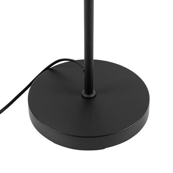 Detailaufnahme des runden, schwarzen Lampenfußes einer Stehlampe.