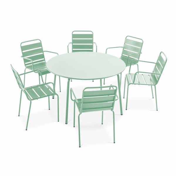 Gartenmöbel-Set aus Metall mit rundem Tisch und fünf Armlehnenstühlen auf einer Holzterrasse vor einer Ziegelwand.